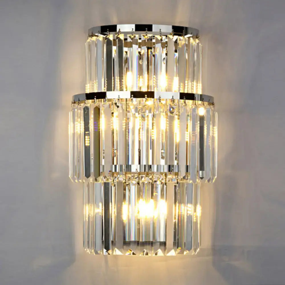 Modern silver crystal three-tiered wall mounted light with cascading clear prisms and polished chrome rings emitting warm glow