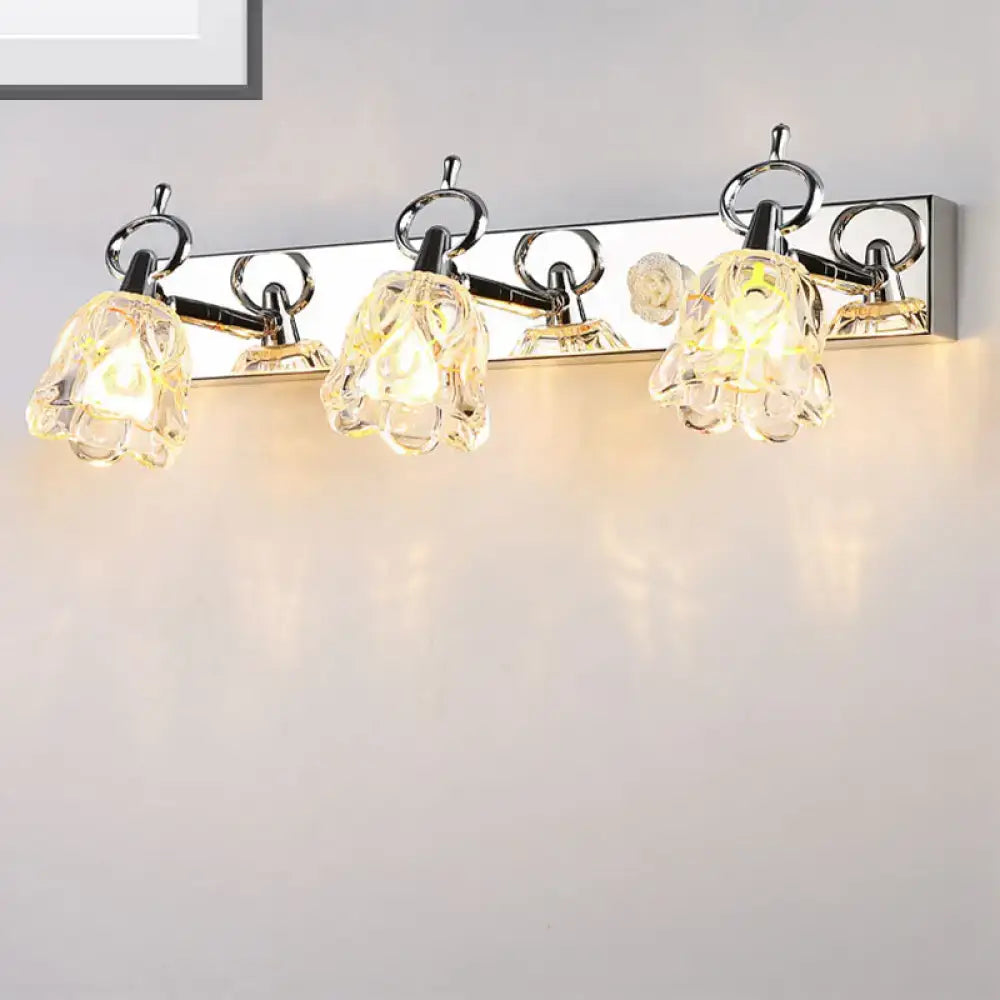 Modern silver finish wall light with clear glass flower-shaped shades emitting warm glow for bathroom use