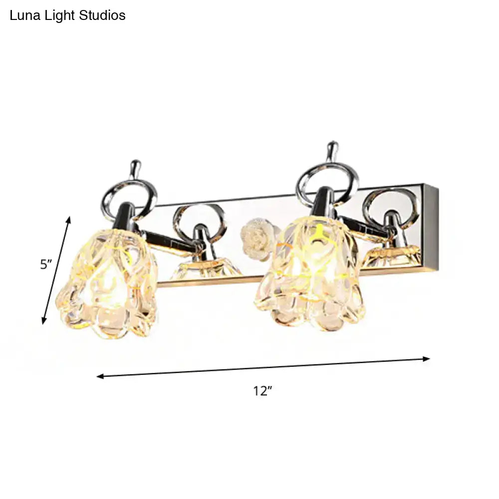 Modern silver finish wall light with clear glass crystal flower shades emitting a warm glow for bathroom use