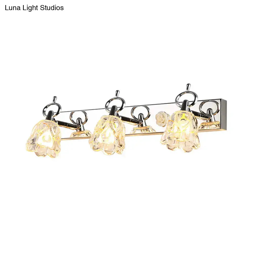 Modern silver finish wall light with three clear glass flower-shaped shades for bathroom vanity lighting