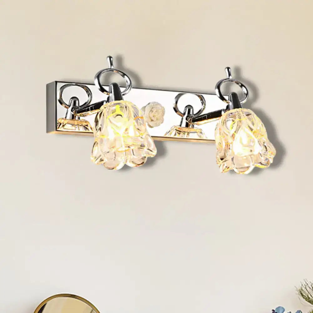 Modern wall light with silver finish and two clear glass flower-shaped shades for bathroom fixture