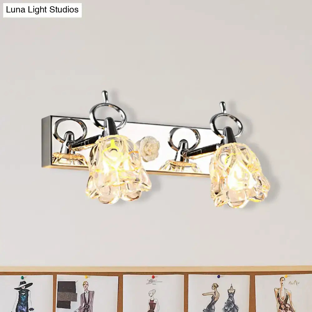 Modern silver finish wall light with clear glass crystal flower-shaped shades emitting warm glow for bathroom use