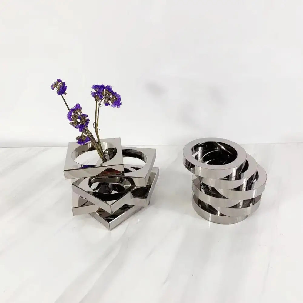 Modern silver geometric circle crystal glass vase with interlocking rings holding dried purple flowers for living room decor