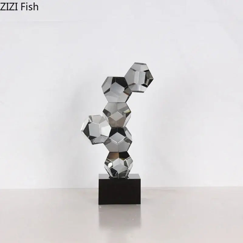 A sleek modern silver geometric crystal ball desk ornament sculpture with interconnected faceted spheres on black base