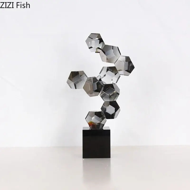 A sleek modern silver geometric crystal ball desk ornament with faceted hexagonal pieces on a black base