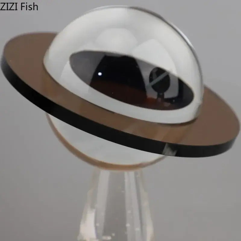 A sleek desk sculpture with a transparent dome glass, reflective black interior, and brown ring decorbites geometric crystal star