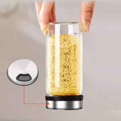 Clear glass seasoning jar with stainless steel lid and base filled with yellow granules from a modern silver set
