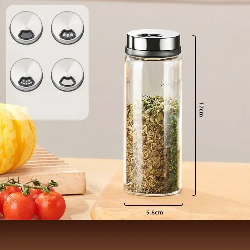 A clear glass seasoning jar with a silver lid and four cat-shaped perforated caps in a modern seasoning jar set