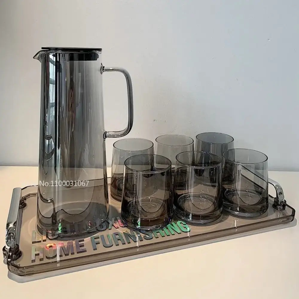 Modern silver glass water pitcher with lid and black handle on a tray with six matching dark gray glass water glasses
