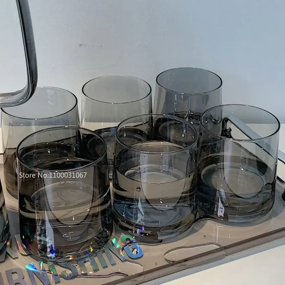 Set of six dark gray transparent glass tumblers with a modern minimalist design for use with a glass water pitcher