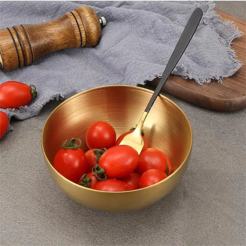 Gold-toned stainless steel mixing bowl from decorbites kitchen set filled with cherry tomatoes and matching spoon