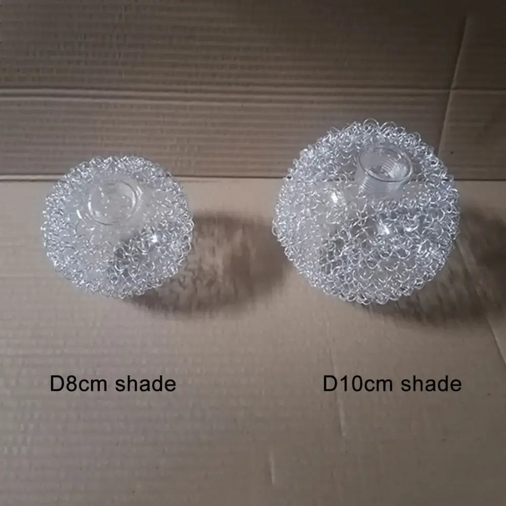 Clear, transparent glass lamp shades with a intricate mesh design and threaded centers.