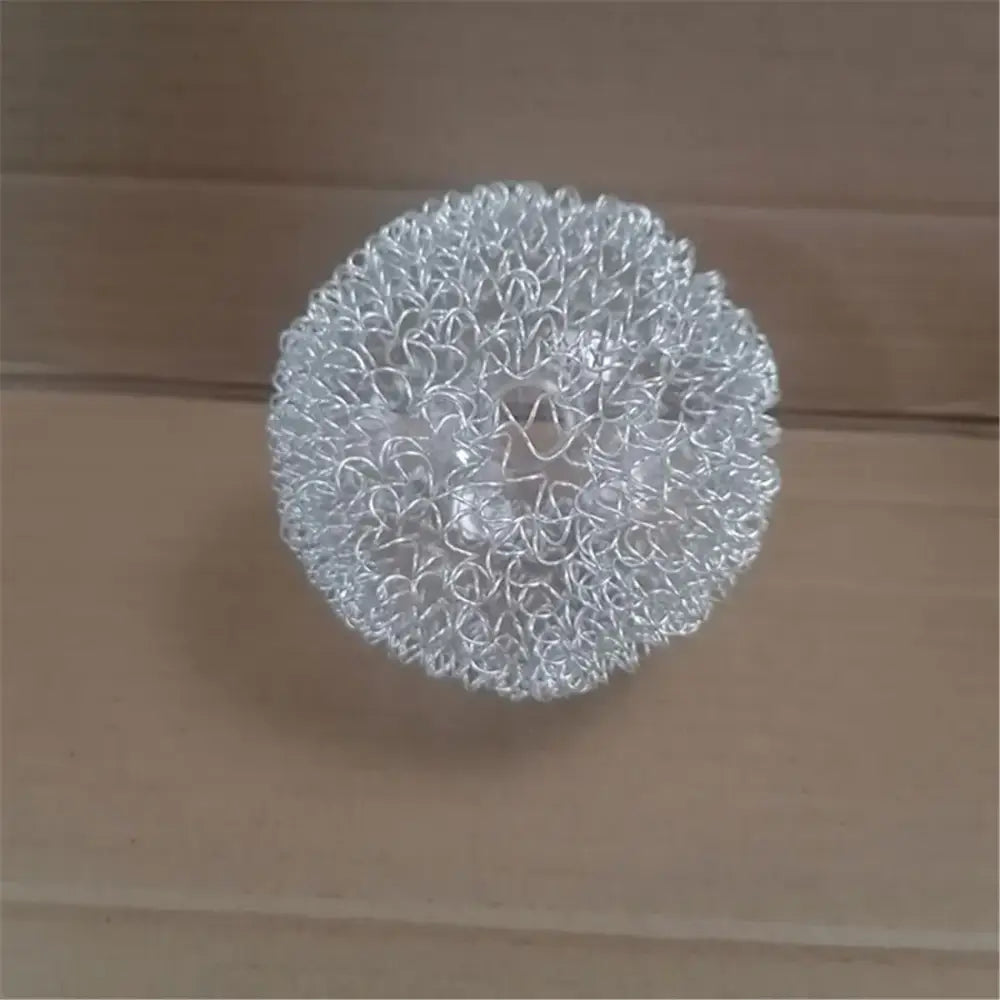 A spherical, silver-colored metal mesh scrubber with a dense, interwoven pattern.