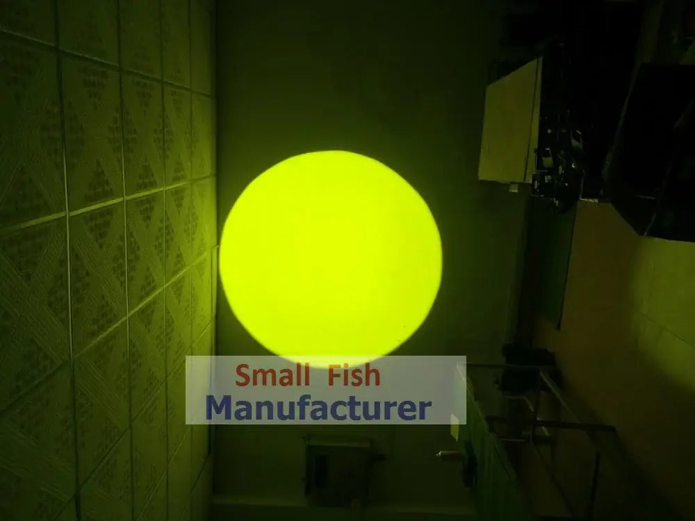 A glowing yellow spherical light fixture of a modern silver metal 300w led follow spot light mounted on a tiled wall