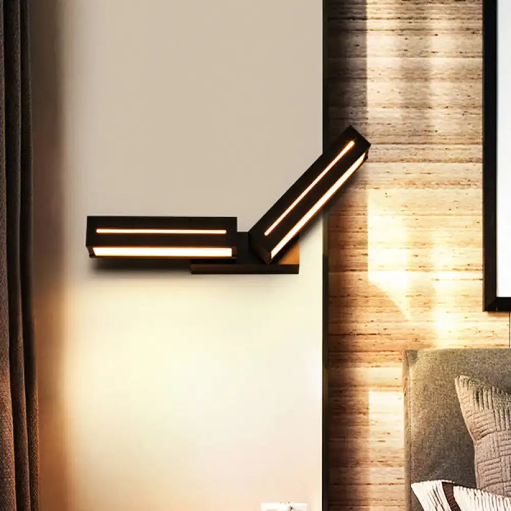 Modern black wall mounted led sconce with two angled light bars emitting warm illumination for bedroom use