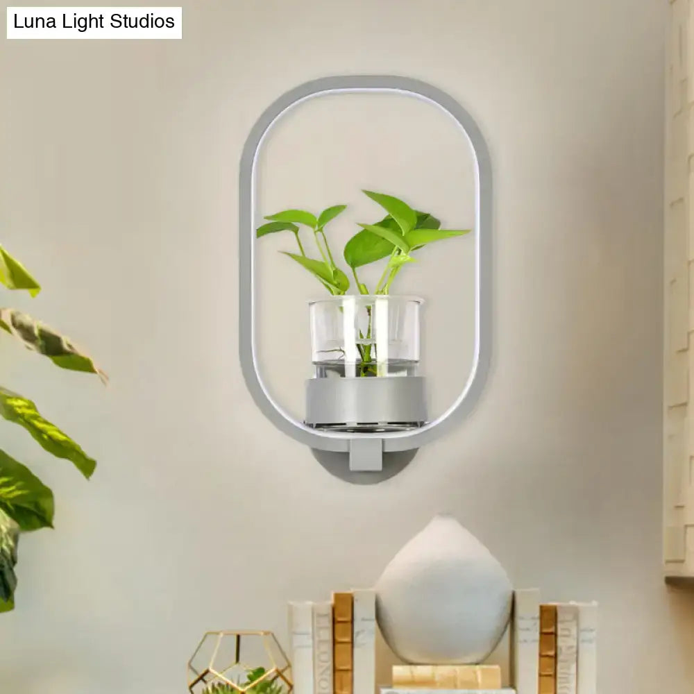 Modern silver wall light with a sleek frame and clear glass plant pot featuring a vibrant green leaf 110v-120v