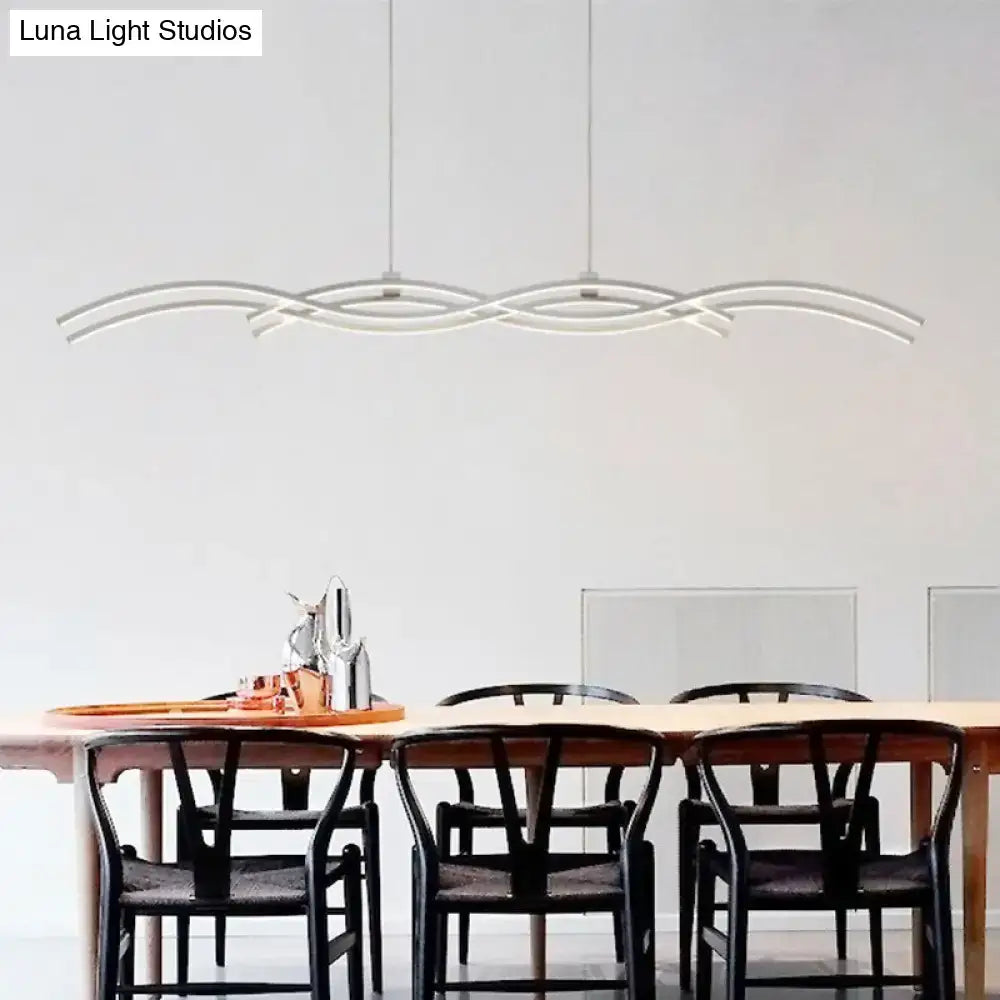 Modern silver wave island pendant light with acrylic curved arms suspended above a dining table by DecorBites