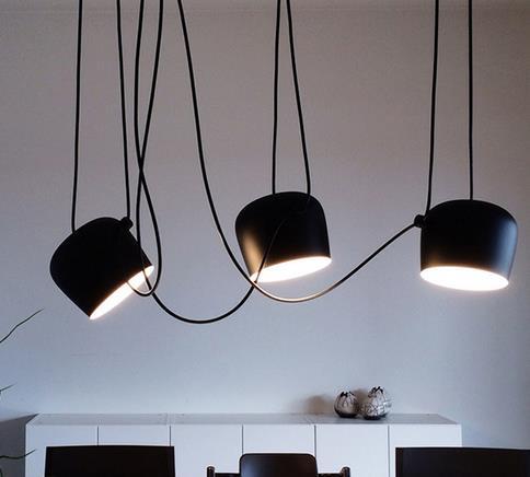 Black matte pendant light with curved cord and three bulb heads, modern design.