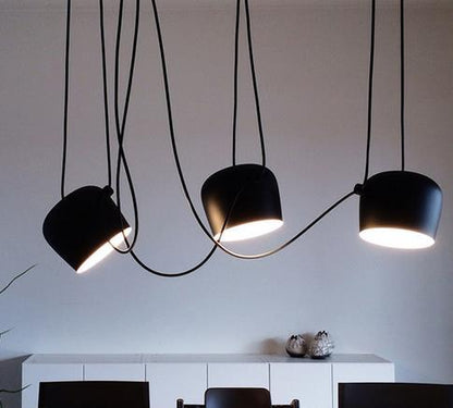 Black matte pendant light with curved cord and three bulb heads, modern design.