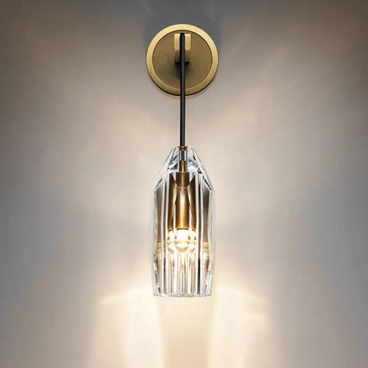 Modern single light brass wall sconce with clear crystal faceted shade and brass accents for bedroom lighting