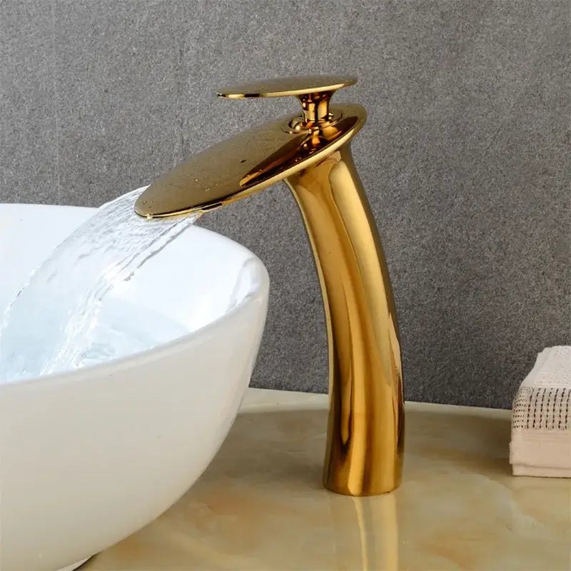 Modern sleek gold waterfall basin faucet with a polished metallic finish and curved spout for bathroom decor