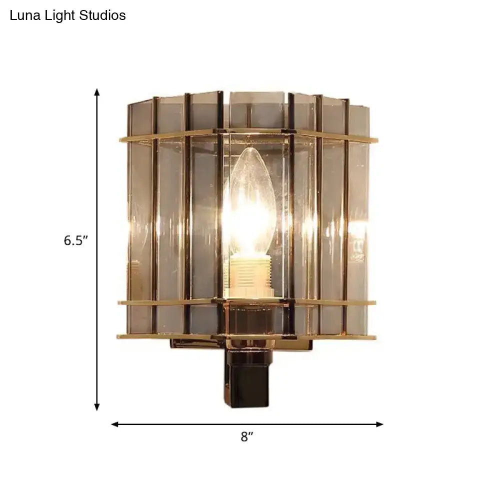 A modern wall light bedroom sconce with a brass frame and smoke gray glass panels featuring an exposed bulb