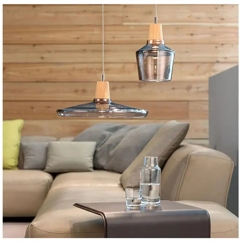 Modern smoked glass and wood pendant light with clear glass shades and wooden accents above a cozy living room