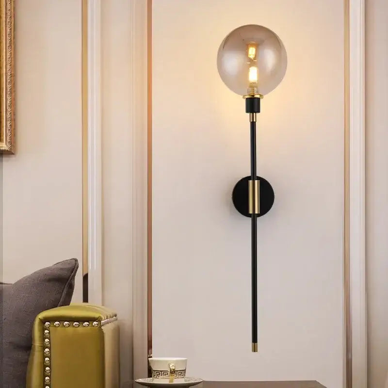 A sleek black and gold wall light with a spherical smoked glass ball led decorbites glass ball bedroom sconce