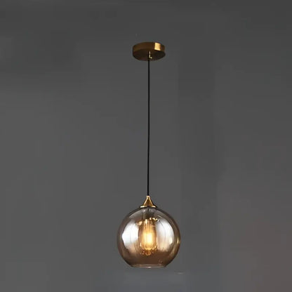 A sleek spherical decorbites glass ball pendant light with amber hue and brass accents for kitchen and dining room decor
