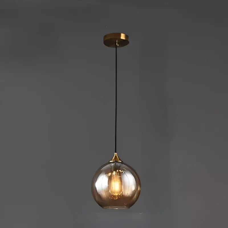 A sleek spherical decorbites glass ball pendant light with amber hue and brass accents for kitchen and dining room decor