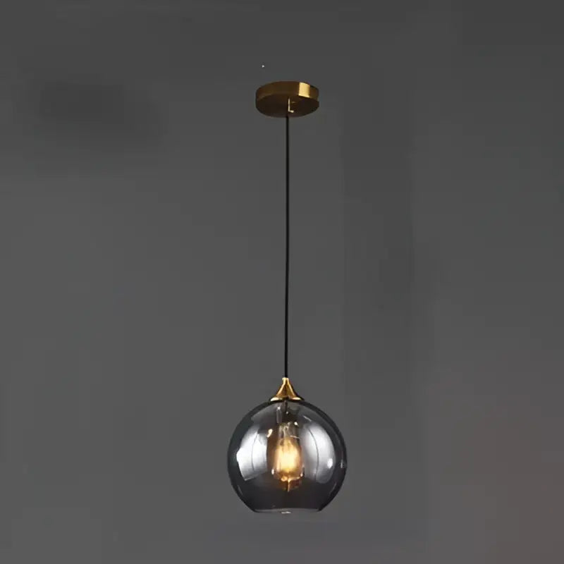 A sleek modern smoked glass ball pendant light with warm glow and brass accents ideal for kitchen and dining room decorbites glass ball pendant lights