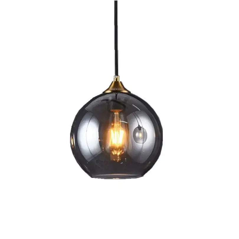 A sleek smoked glass ball pendant light with brass finish and black cord for kitchen and dining room decorbites glass ball