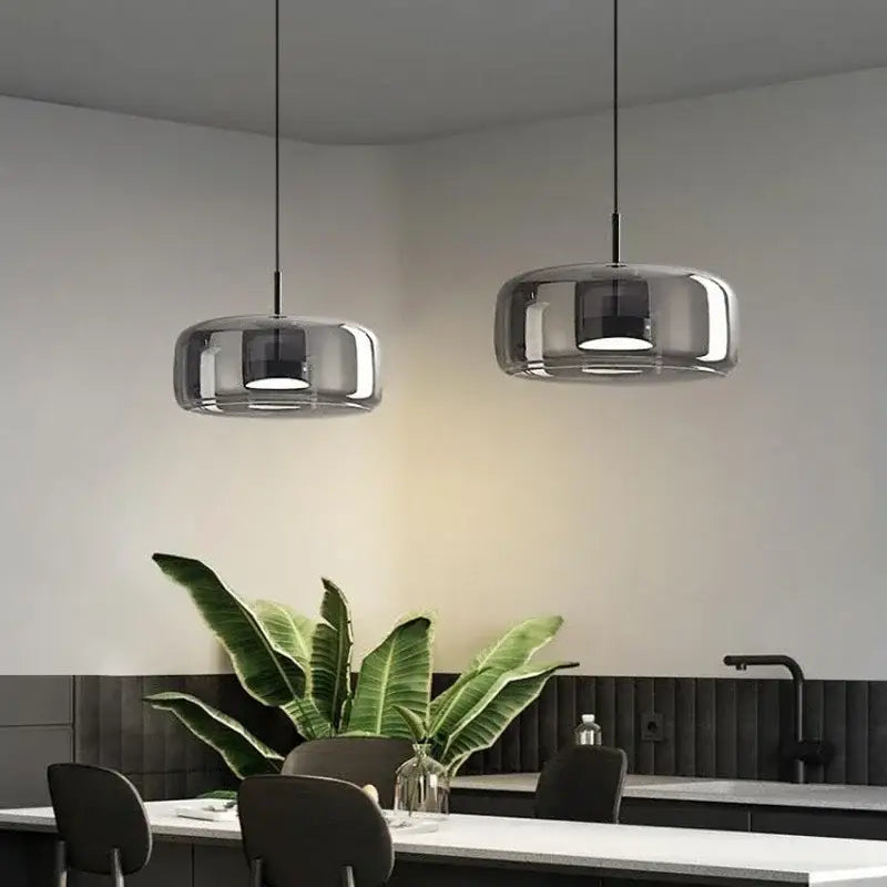 Modern chrome-finished glass bowl chandelier with sleek rounded smoked glass shades hangs above dining area