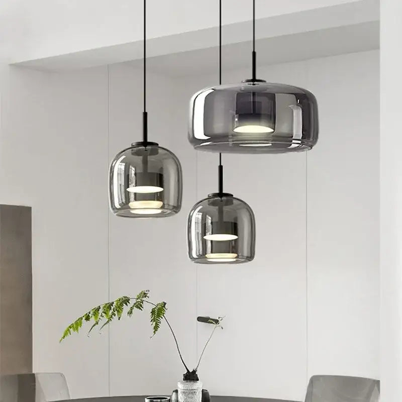 Three modern pendant lights with smoked glass bowl shades and black metal fixtures for dining room chandelier lighting