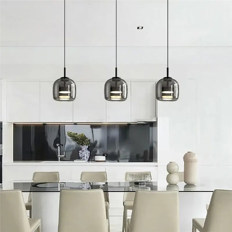 Three sleek dark gray smoked glass bowl chandelier pendant lights with black cords above a modern dining table