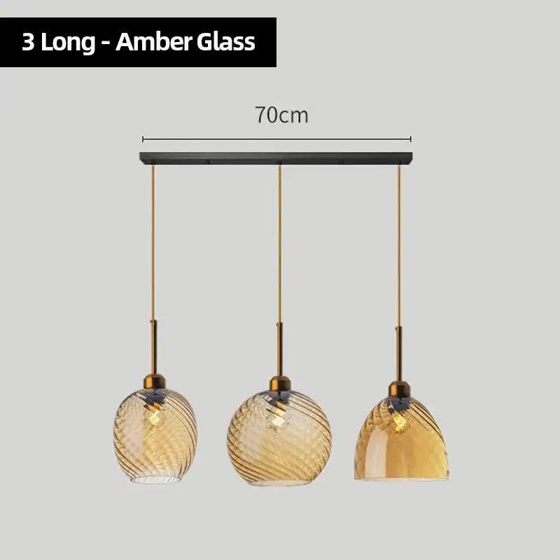 Three amber glass chandelier pendant lights with twisted textured surfaces and gold-toned metal fixtures for kitchen