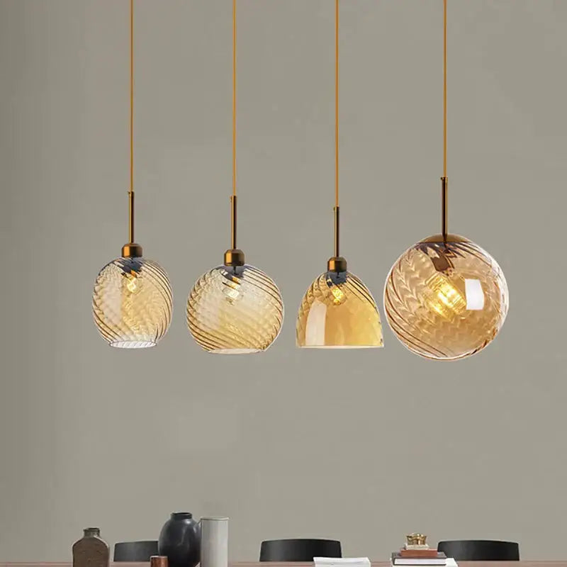 Set of four amber glass chandelier pendant lights with twisted texture and brass fixtures for modern kitchen use