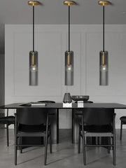 Three modern pendant lights with smoked glass shades and gold-toned decorbites crystal copper fixtures above a black table
