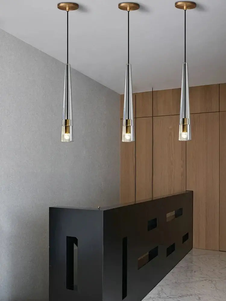Three modern smoked glass crystal copper pendant lights with brass accents hanging in a dining room set decorbites crystal copper