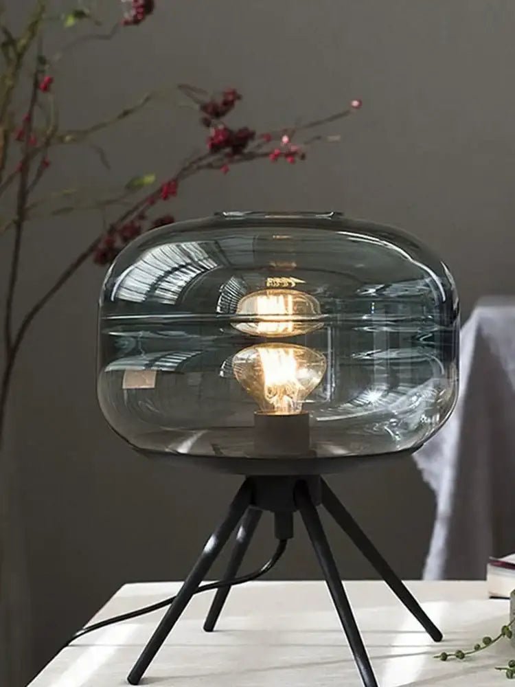 Modern smoked glass desk lamp with a translucent gray glass shade and tripod base for decorbites glass desk use