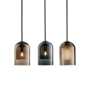Three modern pendant lights with smoked glass led shades and black cords in a glass led chandelier for dining room