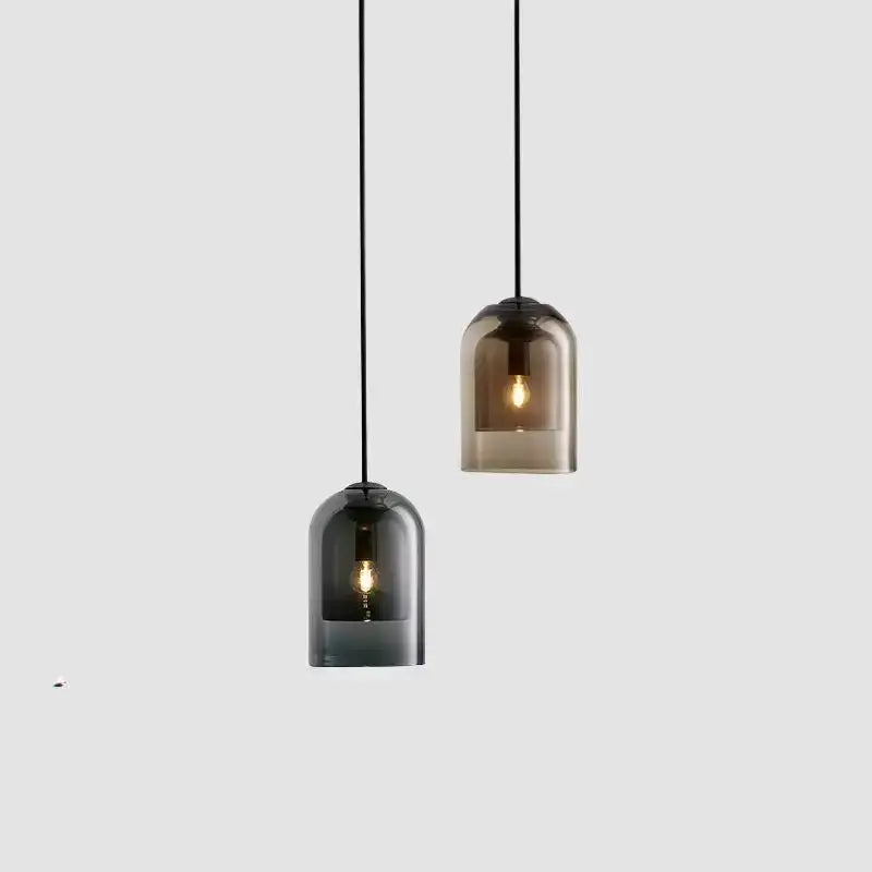 Two sleek smoked glass led chandelier pendant lights with black cords and warm filament bulbs for dining room