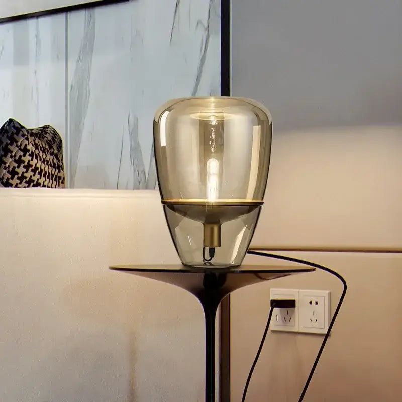 Modern smoked glass table lamp with a translucent amber balloons glass table shade and sleek black metal base for bedroom use