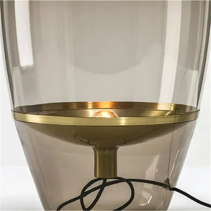 Modern smoked glass table lamp with a translucent smoked glass body and polished brass base for bedroom use