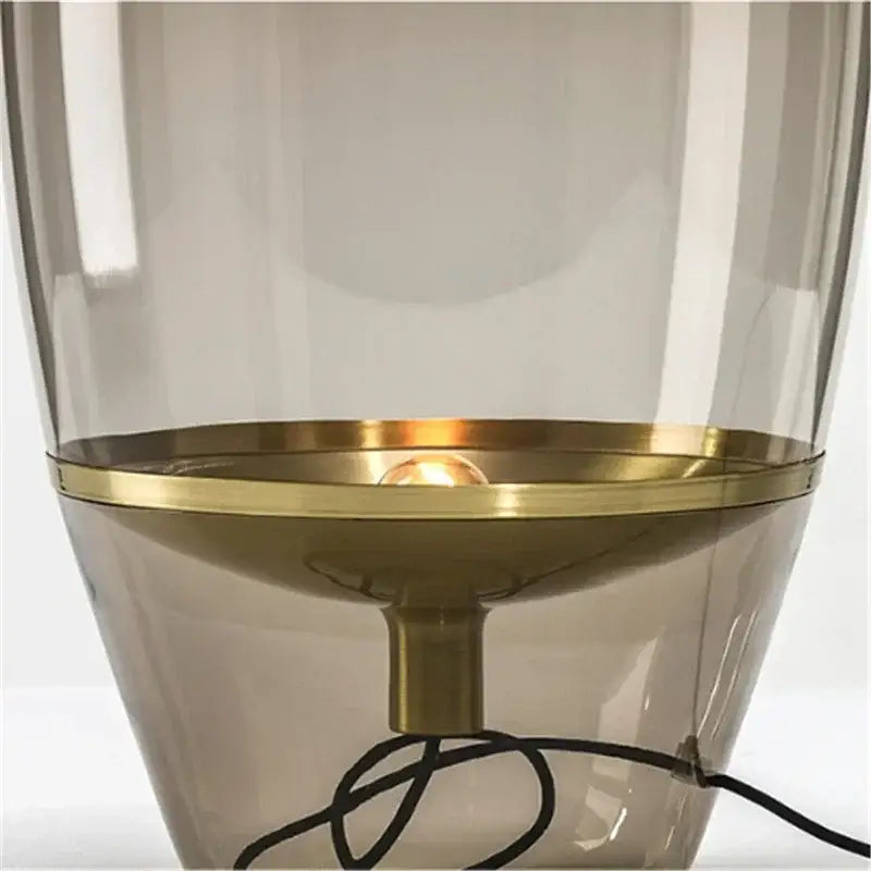 Modern smoked glass table lamp with a translucent smoked glass body and polished brass base for bedroom use