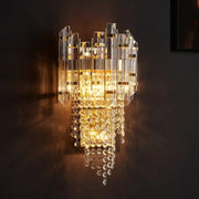 Modern smoky grey crystal wall sconce with vertical glass rods and cascading beads illuminated by warm golden light