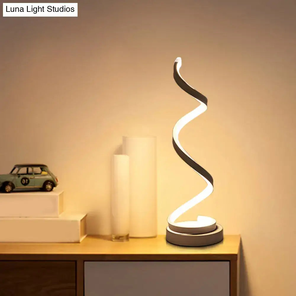 Modern spiral black white gold led table lamp with illuminated curved body casting warm glow for bedroom task light