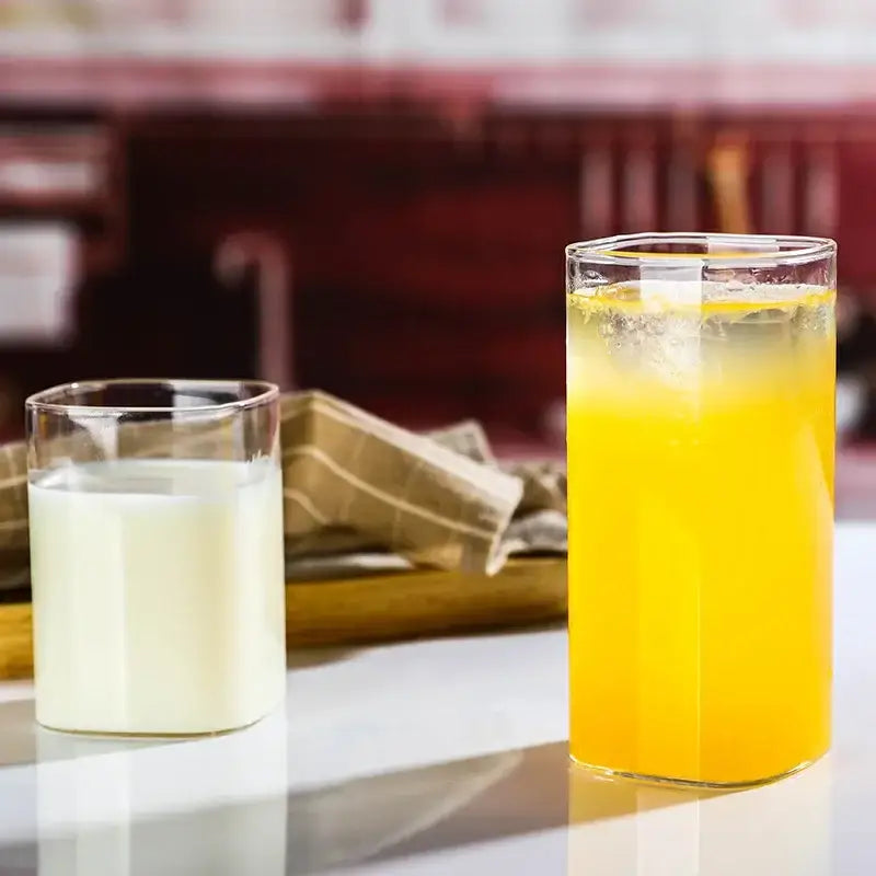 Tall modern square glass coffee tea mug filled with vibrant orange juice and ice cubes without tea mug handle