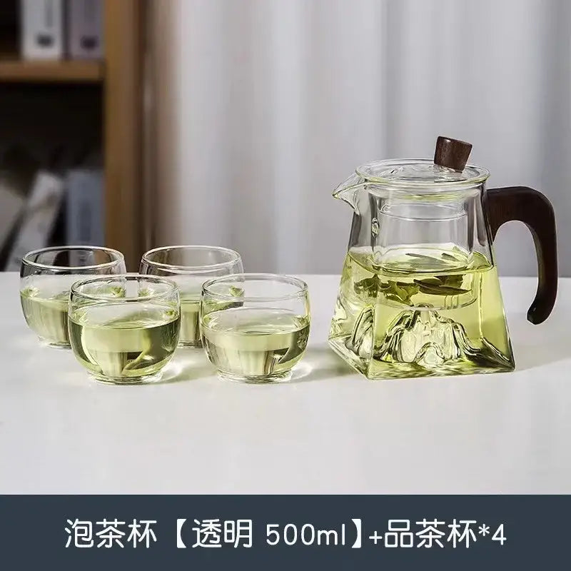 Modern square clear glass tea pot with dark wooden handle and lid featuring intricate mountain-shaped base design