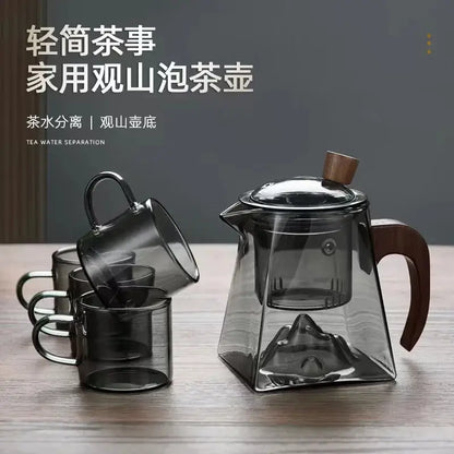Modern square glass tea pot with transparent geometric mountain-shaped base and dark wood handle and lid knob
